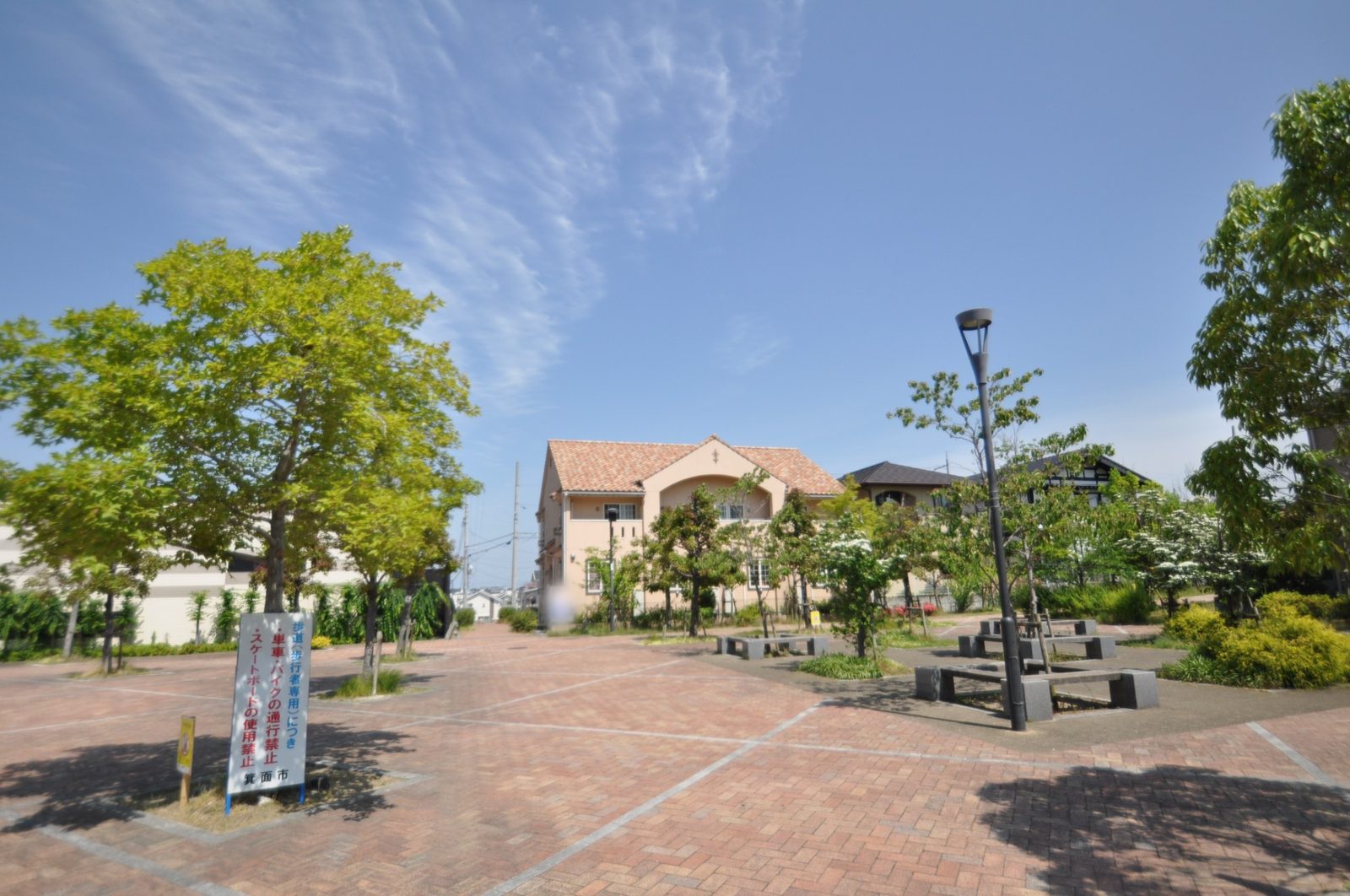 レンガ敷きの遊歩道と並木。奥にアパートが見える