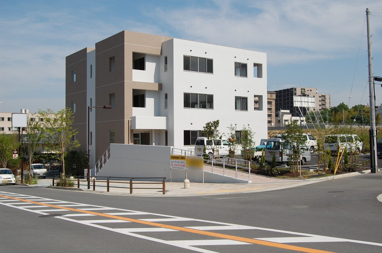 交差点から見たテナントビル。手前に横断歩道と、スロープのある入口